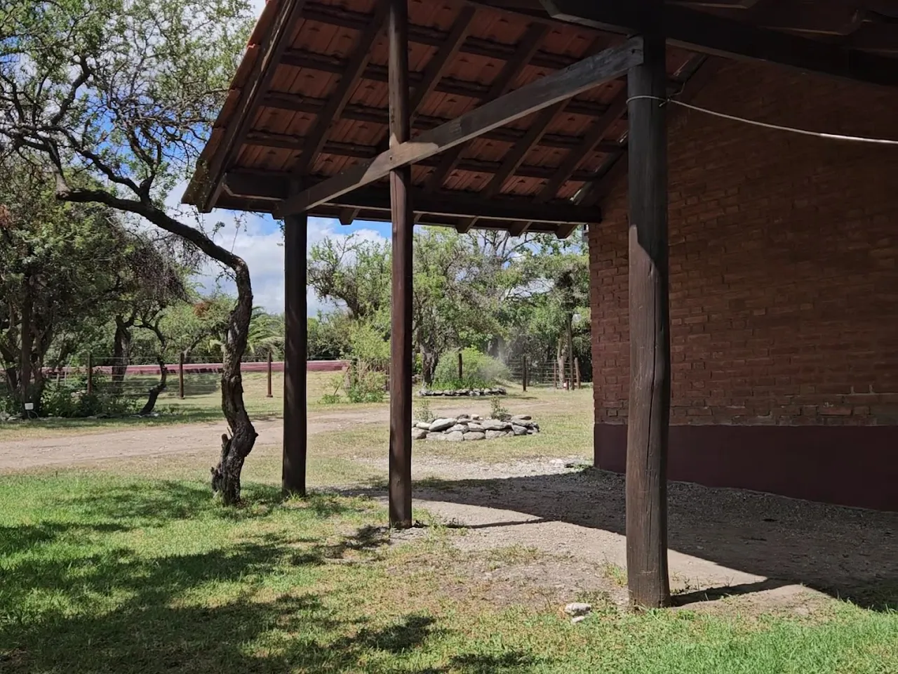 Galería techada de ladrillo y madera junto al parque