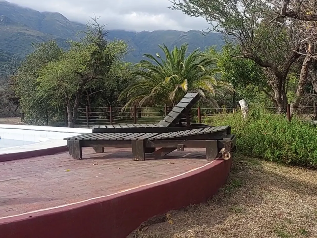 Solárium con reposeras de madera junto a la pileta